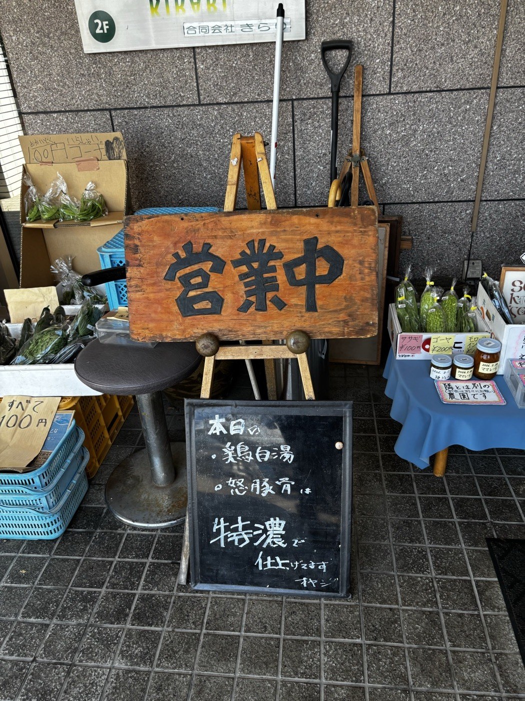 ラーメン常の営業中の看板と黒板。店頭では野菜も売っている