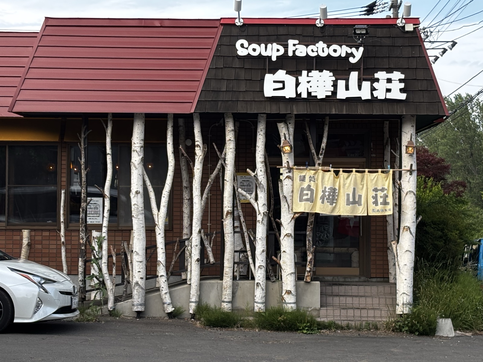 白樺山荘 羊ヶ丘店の外観。白樺の幹が入口にずらりと並ぶ